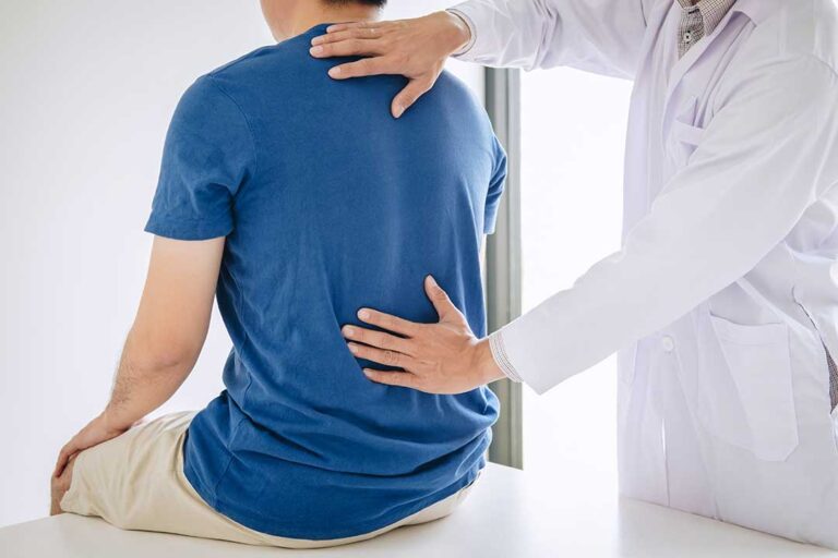 A therapist guides a patient through a controlled exercise beside a treatment table.