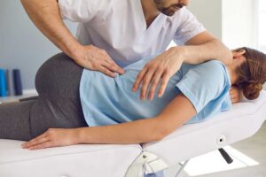 A person applying an ice pack to their knee while sitting comfortably in a home living room.